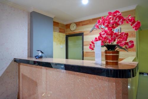 a vase with pink flowers on a counter in a room at RedDoorz near Citraland Waterpark Kendari in Lepoleop