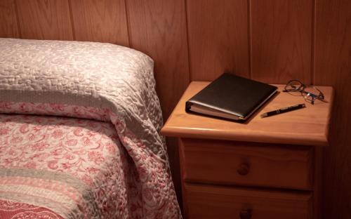 a table with a bed and a book on a night stand at Hostal Durá in Torrellano