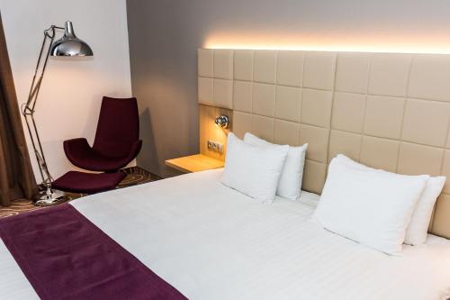 a bedroom with a bed and a red chair at Holiday Inn Budapest-Budaörs by IHG in Budaörs