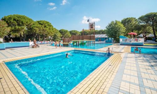 a large swimming pool with people in the water at Estivo Premium Deluxe mobile homes on Camping Ca Savio in Cavallino-Treporti