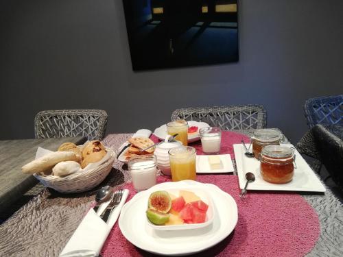 a table with a plate of food and a basket of fruit at Chambre d'hôtes couvent d'Alando in Alando