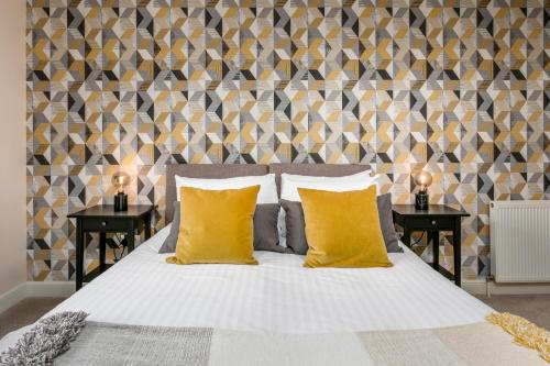 una camera da letto con un letto con cuscini gialli e due tavoli di The Lucas - Donnini Apartments ad Ayr