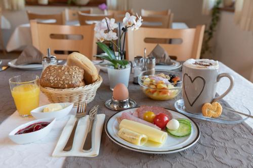 une table garnie d'assiettes de nourriture et de boissons pour le petit-déjeuner dans l'établissement Landhotel Oßwald, à Kirchheim am Ries