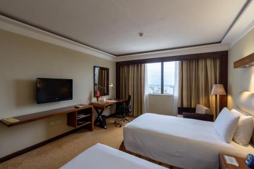 a hotel room with a bed and a desk and a television at Marco Polo Plaza Cebu in Cebu City