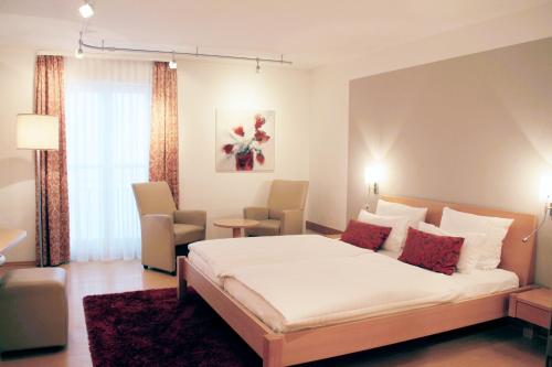 a bedroom with a large bed and two chairs at Hotel Tuchhaus in Volkach