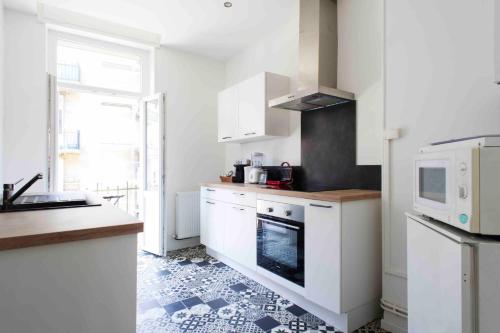 a kitchen with white cabinets and a microwave at Rock in Share - Le Saint-Pierre in Metz