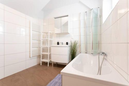 uma casa de banho branca com uma banheira e um lavatório em Penthouse near Schoenbrunn with large terrace! N43 em Viena