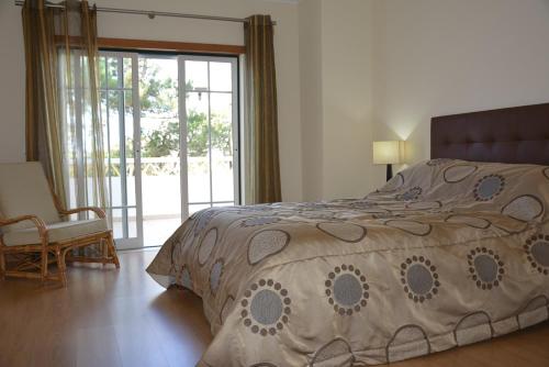 sypialnia z łóżkiem, krzesłem i oknem w obiekcie Paradise Beach Villa w Albufeirze