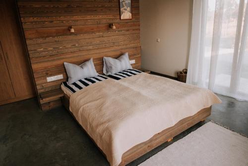 a bedroom with a large bed with a wooden headboard at Magnolia Park in Engure