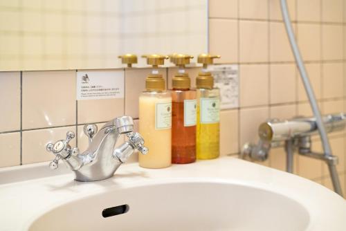 a bathroom sink with three bottles of soap at Plaza Hotel Premier in Fukuoka