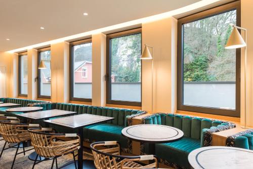 a restaurant with tables and chairs and windows at Mercure Luxembourg Off Kirchberg in Luxembourg