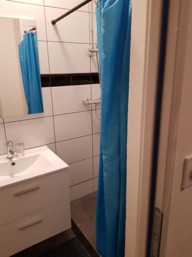 a bathroom with a sink and a blue shower curtain at Appartement moderne Roanne in Roanne