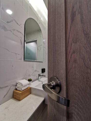 a bathroom with a sink and a door with a mirror at Nappiness Hotel - SHA ExtraPlus in Bangkok