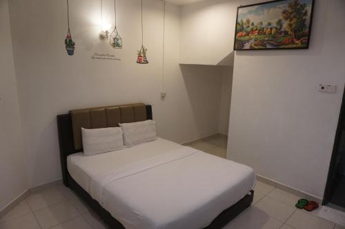 a white bed in a room with a picture on the wall at S & S Guest House Kuantan in Kuantan