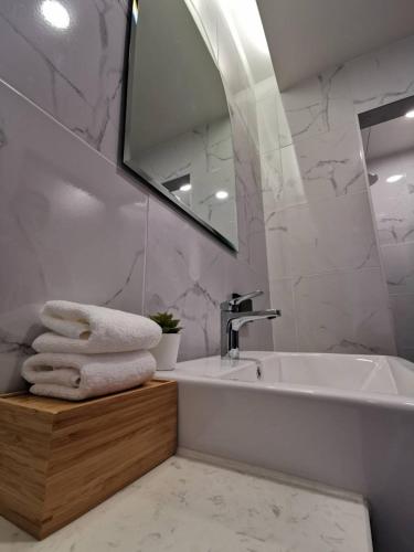 a bathroom with a sink and a mirror and towels at Nappiness Hotel - SHA ExtraPlus in Bangkok