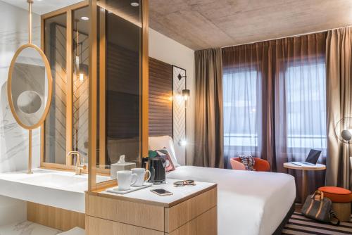 a hotel room with a bed and a sink and a mirror at Mercure Luxembourg Off Kirchberg in Luxembourg