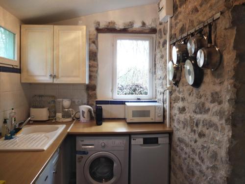 une cuisine avec une machine à laver et une fenêtre dans l'établissement chez capy, à Frayssinet