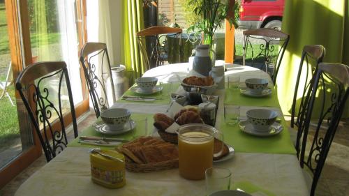 - une table avec petit-déjeuner composé de croissants et de jus d'orange dans l'établissement chambre d'hôtes proche PUY DU FOU, à Le Pin