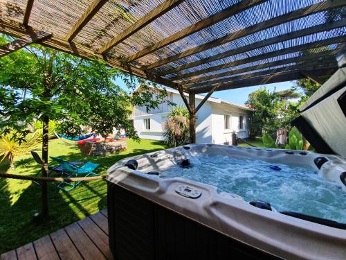 uma banheira de hidromassagem num quintal com uma pérgola em La Maison Bisca em Biscarrosse-Plage