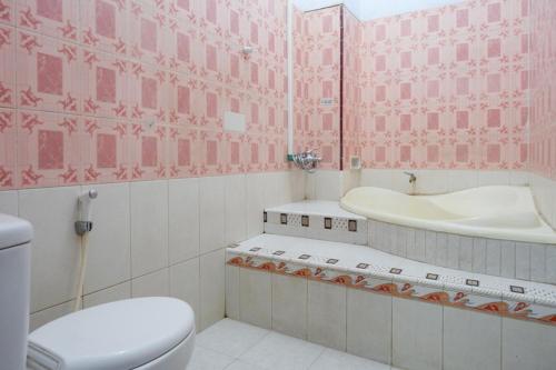 a pink bathroom with a toilet and a sink at RedDoorz Plus Syariah near Stasiun Pekalongan 2 in Pekalongan