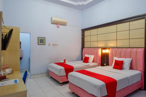 a hotel room with two beds and a television at RedDoorz Plus Syariah near Stasiun Pekalongan 2 in Pekalongan