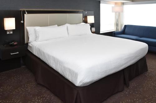 a bedroom with a large bed and a blue chair at Holiday Inn Canton-Belden Village by IHG in Canton
