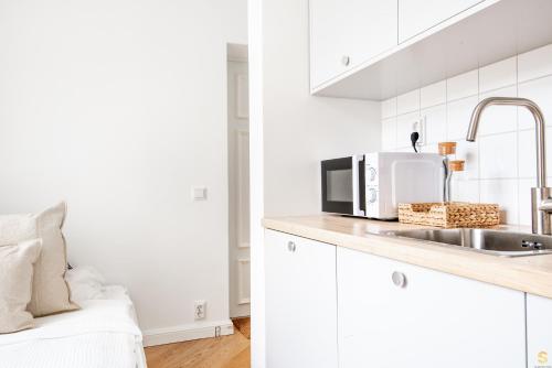 een witte keuken met een wastafel en een magnetron bij Pieni Roobertinkatu Small 13 in Helsinki