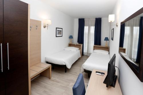 Cette chambre comprend deux lits et un bureau. dans l'établissement Hotel Giardino d'Europa, à Rome