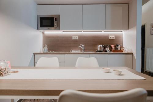 uma cozinha com armários brancos e uma mesa com cadeiras em Kényelmes apartman a belváros szélén em Gyor