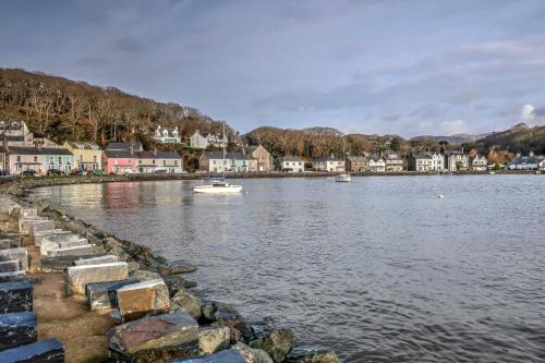 a body of water with houses and a small boat at 7 Mersey Street, Borth-y-Gest in Porthmadog