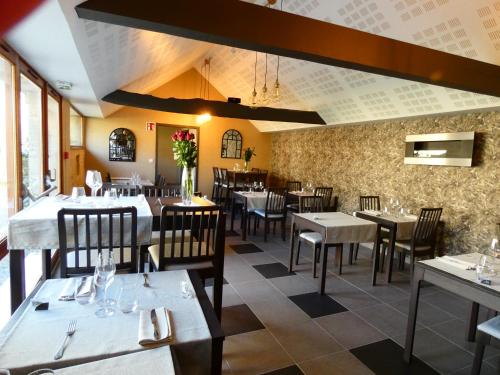 a dining room with tables and chairs in a restaurant at Hôtel Restaurant le clos de l 'Ancien Pressoir in Commes
