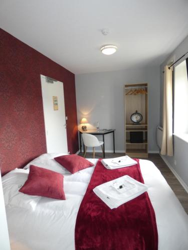 a bedroom with a large white bed with red pillows at Hôtel Restaurant le clos de l 'Ancien Pressoir in Commes