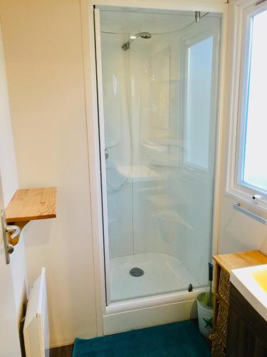 une douche avec une porte vitrée dans une salle de bain dans l'établissement Le Sherwood - Mobil-Home, à Saint-Jean-de-Monts