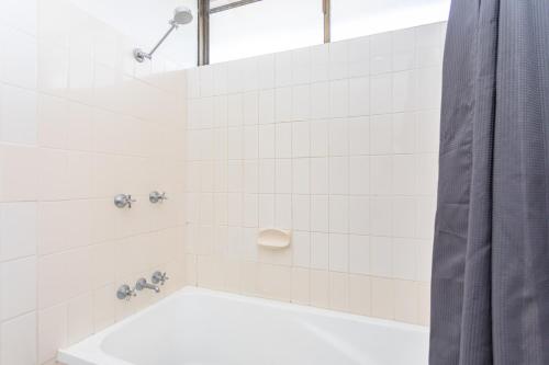 a white tiled bathroom with a shower and a tub at OCEAN VIEWS 10 in Airlie Beach