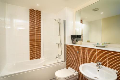 y baño con aseo, lavabo y ducha. en Coastal City Rooms - Waterfront en Swansea