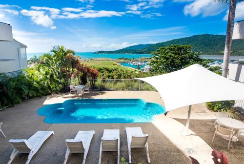 a view of a pool with chairs and an umbrella at OCEAN VIEWS 10 in Airlie Beach