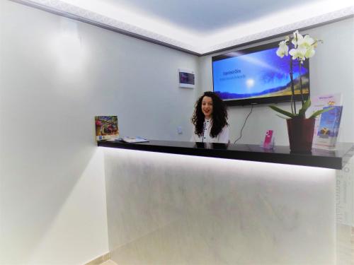 a woman standing behind a counter in a room with a tv at Costa Point Chios in Chios
