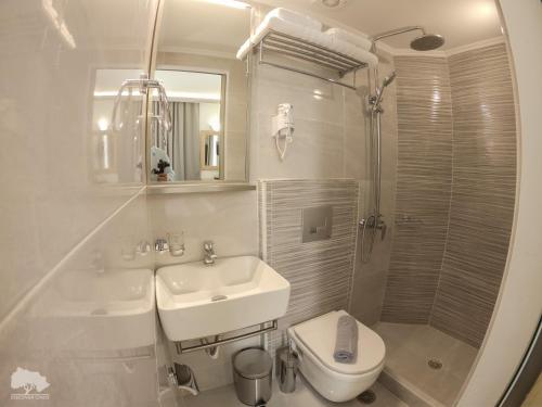 a white bathroom with a sink and a toilet at Costa Point Chios in Chios