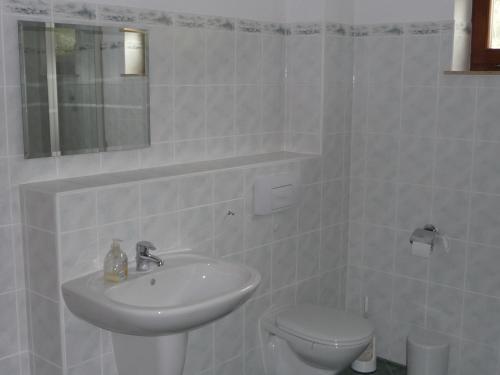 a white bathroom with a sink and a toilet at Ferienwohnung Wilsdruff - Kaufbach in Wilsdruff