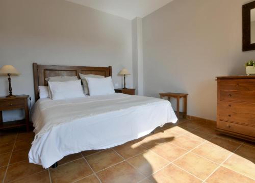 1 dormitorio con 1 cama blanca con 2 mesitas de noche y vestidor en apartamento campo de golf Isla Canela en Isla Canela