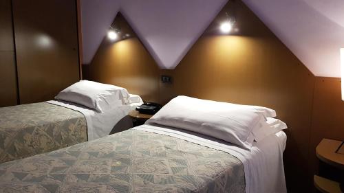 a hotel room with two beds and lights on the wall at Addaura Village e Congressi in Mondello