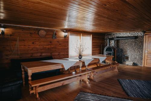 a dining room with wooden walls and wooden tables at Viesu nams RŪĶĪŠI in Rugāji