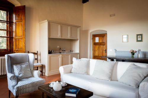 a living room with a white couch and a chair at Castello Vicchiomaggio in Greve in Chianti