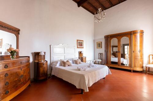 a bedroom with a bed and a dresser and a mirror at Castello Vicchiomaggio in Greve in Chianti