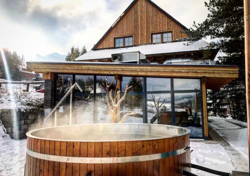 a hot tub in front of a house in the snow at Drevenica Desina in Terchová