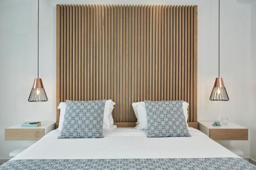 a bedroom with a bed with two blue and white pillows at Grand Beach Hotel in Mýkonos City