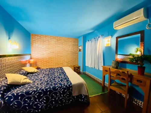 Dormitorio azul con cama y espejo en La Estancia Villa Rosillo, en Aracena