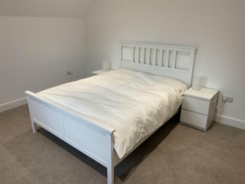 a bedroom with a white bed and a night stand at The Smiddy House in Auchterarder