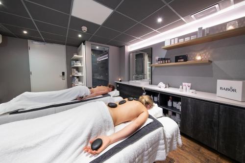 two women laying on beds in a spa room at Bilderberg Kasteel Vaalsbroek in Vaals