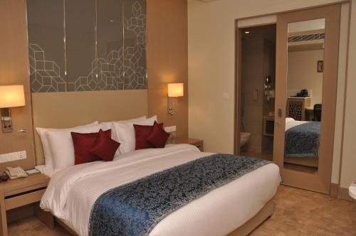 a hotel room with a large bed and a mirror at Days Hotel Jaipur Tonk Road By Wyndham in Jaipur